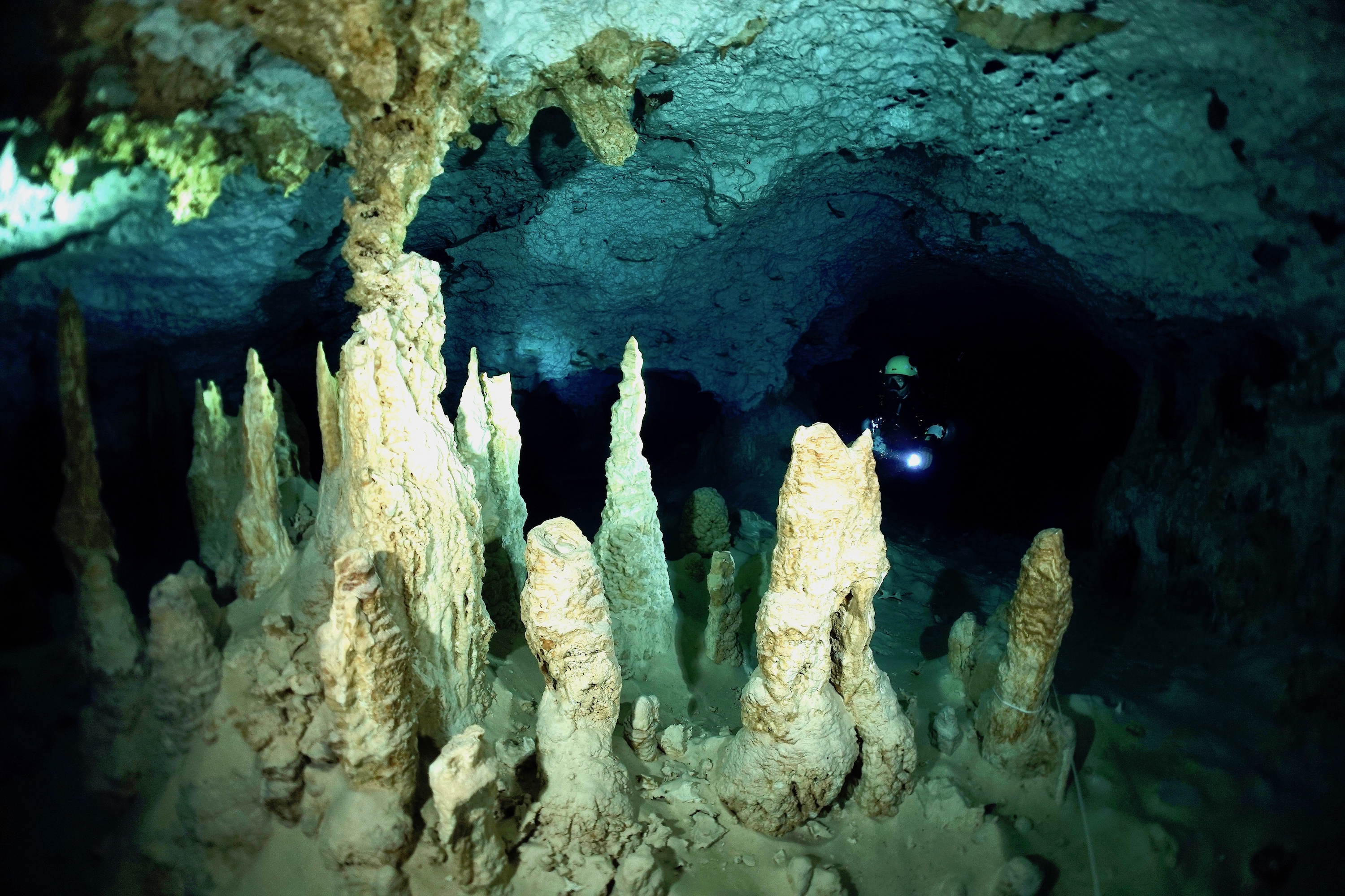 Diver with cluster of stalagmites in Cenote Calavera. Photo by Pierre Constant