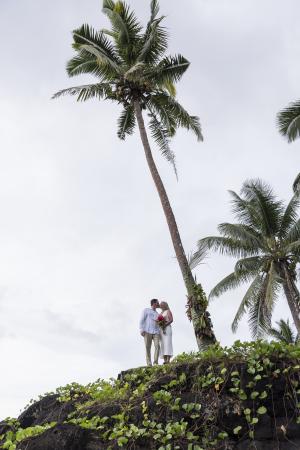 Newlyweds posing for photos on a bluff overlooking the Pacific Ocean at Paradise Taveuni