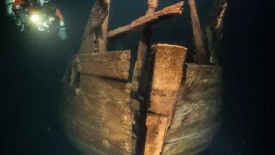 Stern of the wreck. The stern post ends to opening in planking, tiller moved in it. The transom has been above this structure. Uppermost planks on the sides of the stern have fallen away.