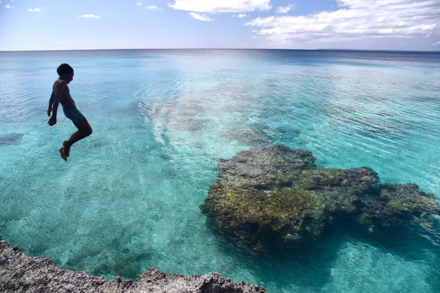 Young boy jumping into the heart of Lifou at Peng Beach, Lifou, New Caledonia. Photo by Pierre Constant