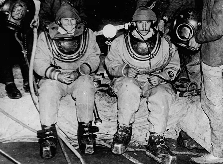 Penelope Powell and Graham Balcombe kitted up in Wookey Hole Cave for the first ever cave dive in 1935. Historical photo courtesy of Mendip Cave Registry and Archive Cave Diving Group.