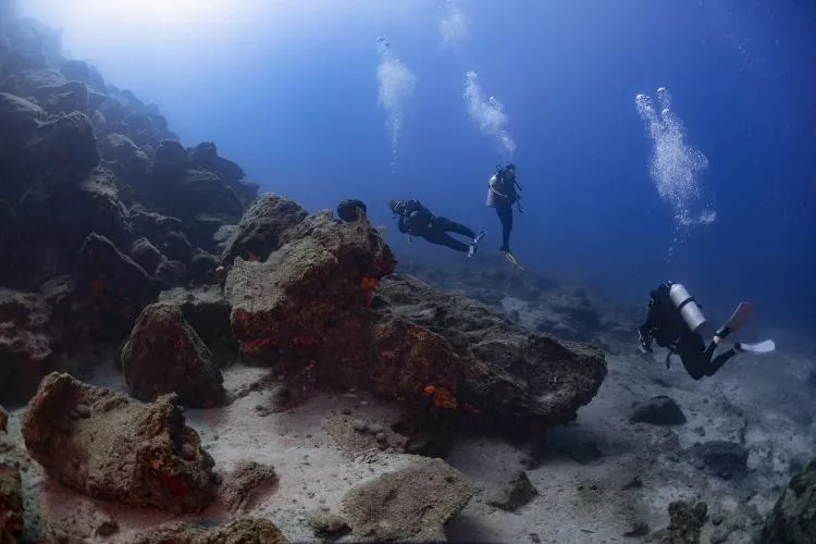 Divers exploring the rocky terrain at Karaada dive site