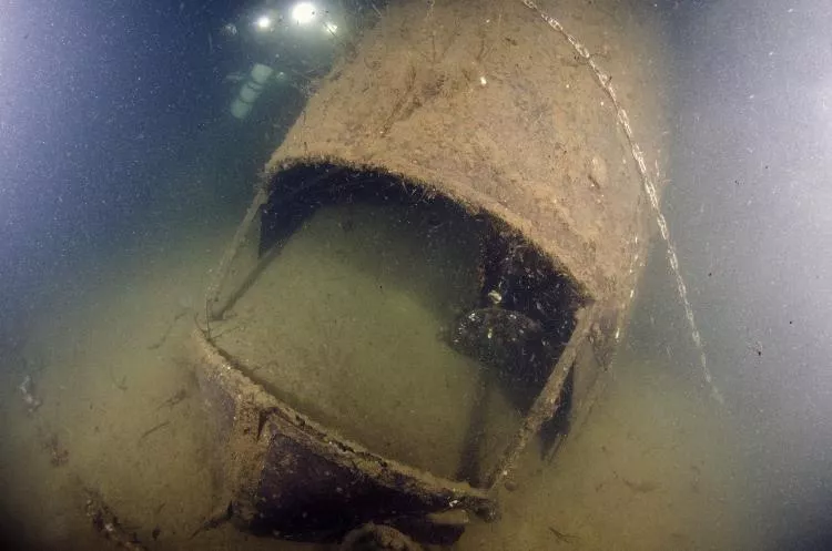 The exposed cockpit of the Hudson plane wreck, with its nose partially buried in the seabed 